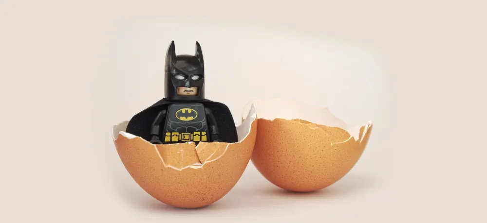 A Lego Batman figure hatching from an eggshell